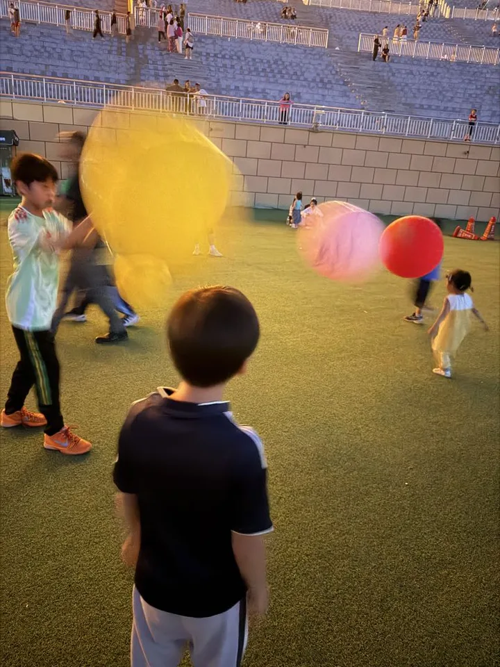 A child playing with a huge yellow balloon on the field at Lanshan Park