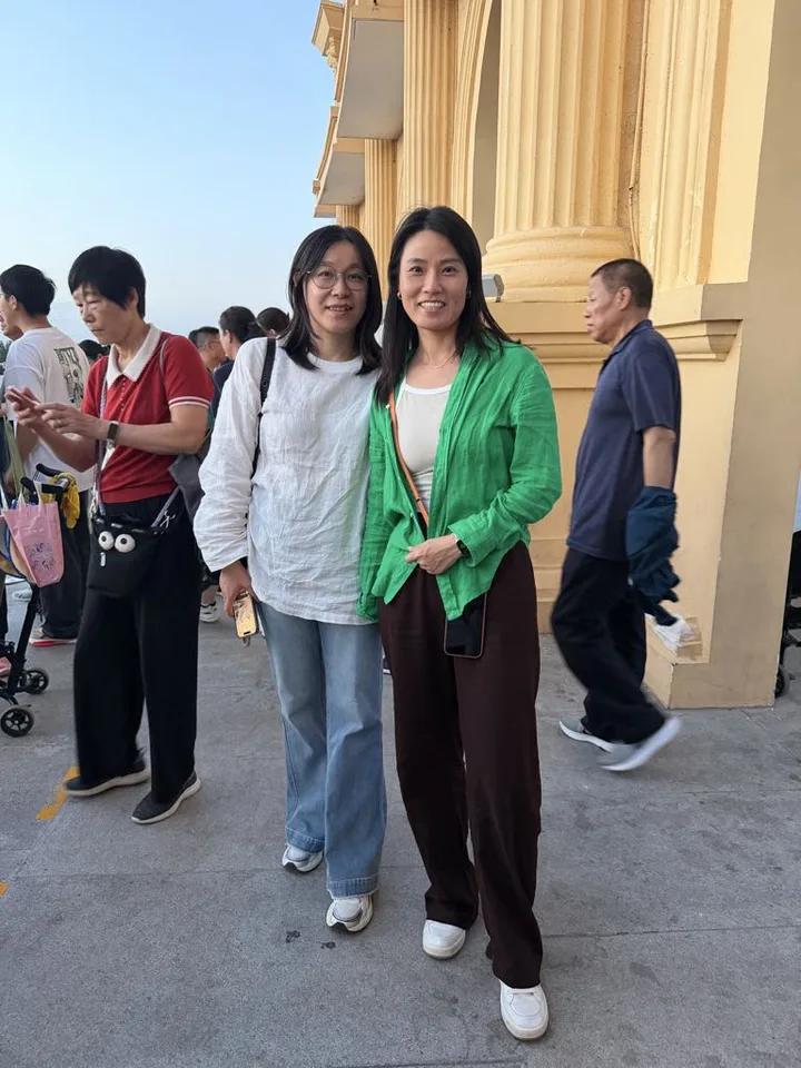 Two visitors together beside the golden arches at Lanshan Park